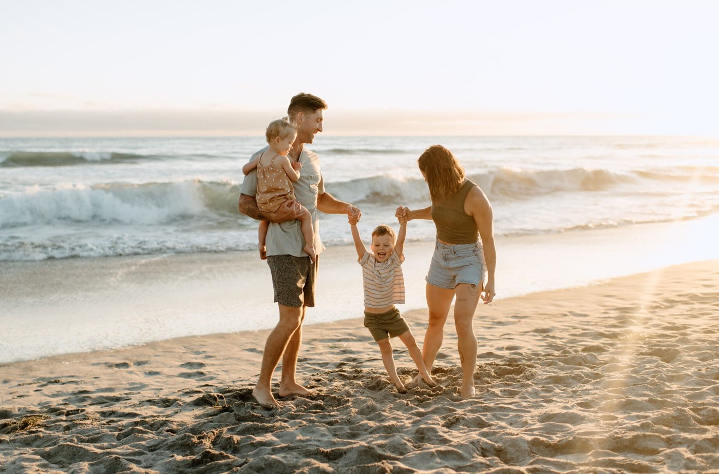 A family playing together on the beach at sunset.